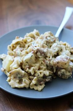 a blue plate topped with macaroni and cheese on top of a wooden table