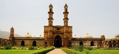 an old building with two towers in the middle of a grassy area next to a path