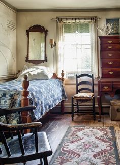 a bedroom with a bed, dresser and chair next to a rug on the floor