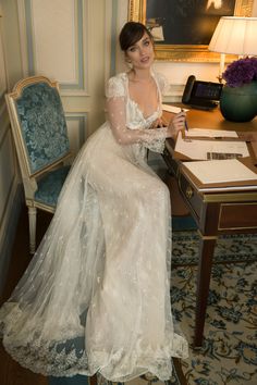 a woman in a white dress sitting at a desk