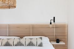 a bed with a wooden headboard and white sheets in a room that has wood slats on the wall