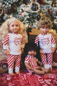 three dolls are posed in front of a christmas tree