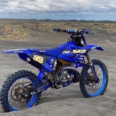 a blue dirt bike parked in the sand