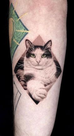 a black and white cat with green eyes in a diamond shape tattoo on the leg