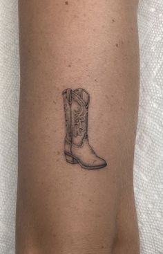 a small tattoo on the leg of a woman's legs with a cowboy boot