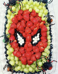 a spider man made out of fruit in the shape of grapes and strawberries on a platter