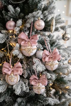 ornaments are hanging from the christmas tree in pink and silver colors, with bows on them