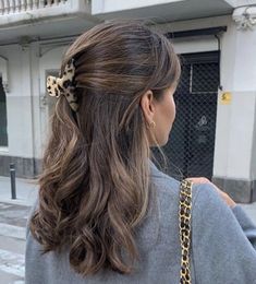 a woman with long hair and a leopard print bow in her hair is walking down the street