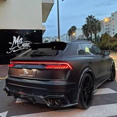 the rear end of a black car parked in front of a building