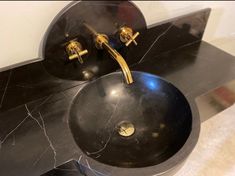 two black sinks with gold faucets on top of them and marble counter tops