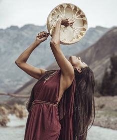 a woman in a red dress is holding a frisbee up to her head