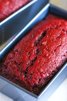 two pans filled with red cake sitting on top of a table