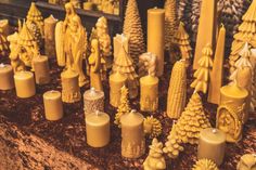 yellow candles are lined up in rows on the table next to pine cones and other decorations