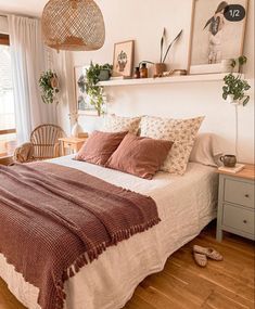 a bed sitting in a bedroom next to a window with plants on top of it