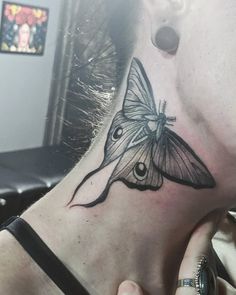 a woman with a black and white butterfly tattoo on her neck, behind her ear