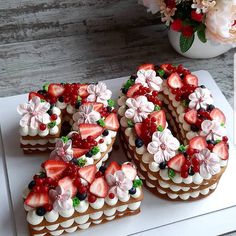 a number shaped cake sitting on top of a white cutting board next to a vase with flowers