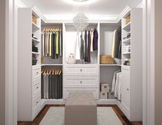 a walk in closet with white cabinets and drawers, chandelier hanging from the ceiling