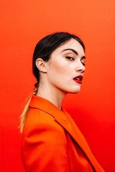 a woman in an orange dress with her eyes closed and red lipstick on the lips