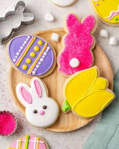 decorated cookies on a wooden plate with bunny ears and other decorations around it, including sugar