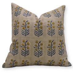 a beige pillow with blue and yellow florals on it's side, against a white background