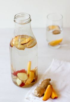 a glass jar filled with sliced up fruit next to a white napkin on top of a table