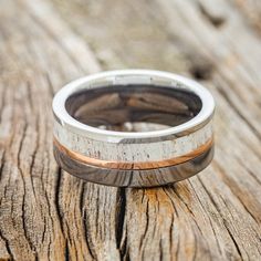 a wedding band with wood inlays on an old piece of wood that is being used as a ring