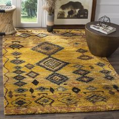 a yellow area rug with an ornate design on the top and bottom, in front of a window