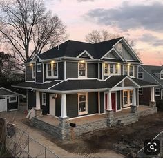 a large house with lots of windows and lights on it's front porch at dusk