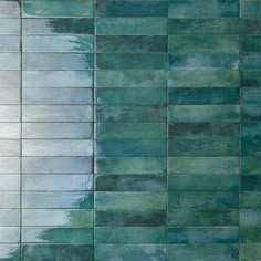 a green tiled wall with white and blue tiles on the bottom, in an abstract pattern