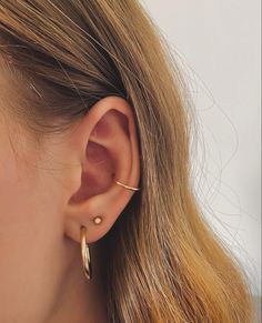 a close up of a woman's ear with two small gold hoops on it