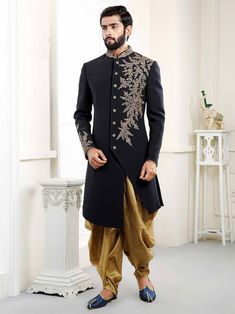 a man in a black and gold sherwa with golden pants, standing next to a