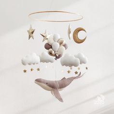 a baby mobile with a dolphin and stars hanging from it's side in the air