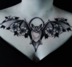 a woman's chest with a bat and flowers on it