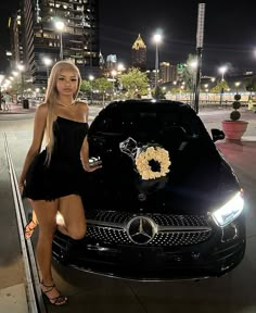 a woman standing next to a black car