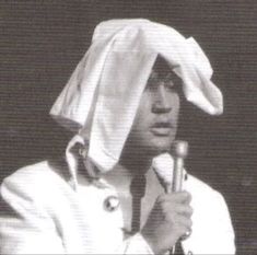 a black and white photo of a person wearing a hat with a microphone in his hand