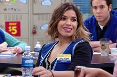 three people sitting at a table with food and drinks in front of them, one woman is smiling