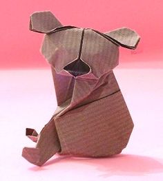 an origami bear sitting on the ground in front of a pink background with its mouth open