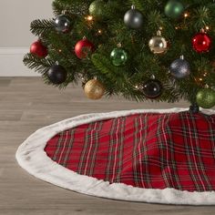 a christmas tree with ornaments on it and a red plaid blanket under the tree skirt