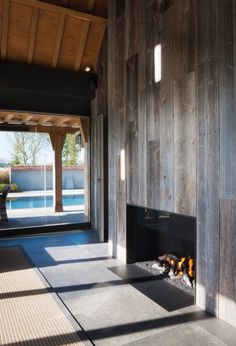 an empty room with a fire place and large glass doors that open to the pool