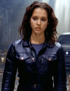 a woman standing in the middle of a street wearing a black leather jacket and jeans