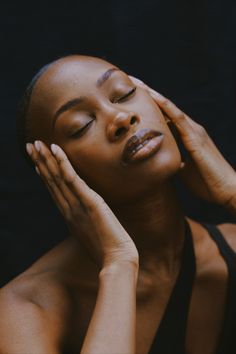 a woman with her eyes closed holding her hand to her face and touching her cheek