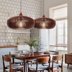 a dining room table with chairs and lights above it