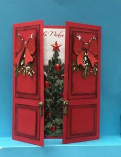 an open red door with a christmas tree in the center and decorations on it's sides