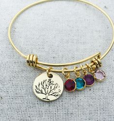 "This listing includes a gold plated stainless steel bangle bracelet. Bracelet includes a 5/8\" nu gold, brass disc hand stamped with tree and gold plated Swarovski birthstone crystal charms. PLEASE INCLUDE IN THE NOTE TO SELLER SECTION AT CHECKOUT THE BIRTHSTONES NEEDED IN THE ORDER YOU WOULD LIKE THEM ON THE BANGLE. Nu-gold is a copper alloy consisting of 85% copper and 15% zinc. It has a rich warm color and if highly polished resembles gold. This is also known as jewelers brass and will tarni Mother's Day Tree Of Life Pendant Jewelry, 14k Yellow Gold Tree Of Life Jewelry, Elegant Yellow Gold Tree Of Life Jewelry, 14k Gold Tree Of Life Pendant Jewelry, Tree Of Life Jewelry Inspire Uplift ⭐, Mother Jewelry, Stainless Steel Bangles, Family Jewellery, Crystal Charm