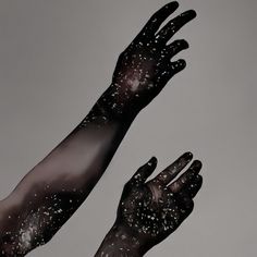 two hands with black paint on them reaching up into the air to touch each other