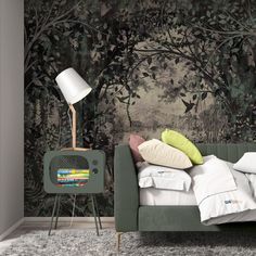 a green couch with pillows on it next to a lamp and wallpaper in the background