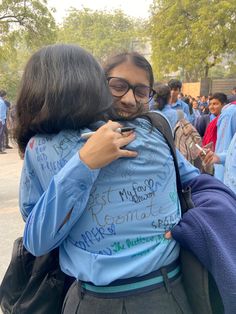 two women hugging each other in the middle of a crowd