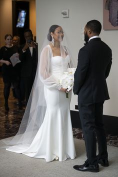 the bride and groom are looking at each other as they stand in front of their guests