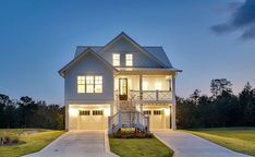 a large white house with lots of windows and lights on it's front porch