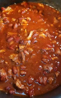 a pot filled with beans and meat on top of a stove